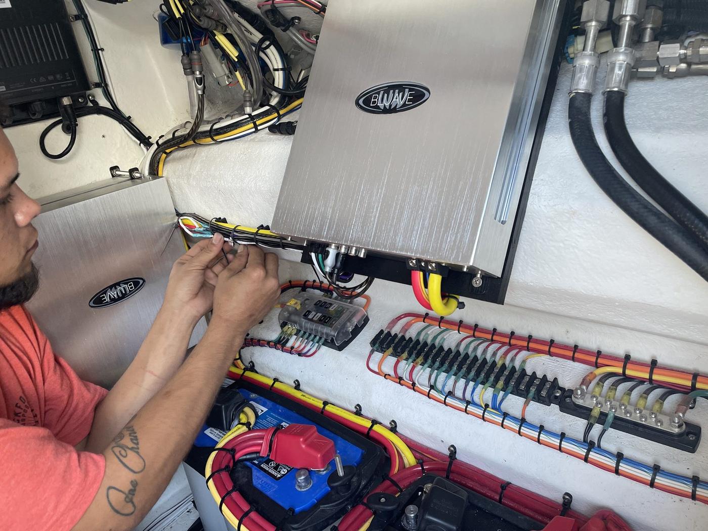SoundWorkZ technician hand-wiring a marine amplifier with color-coded, loomed cable runs