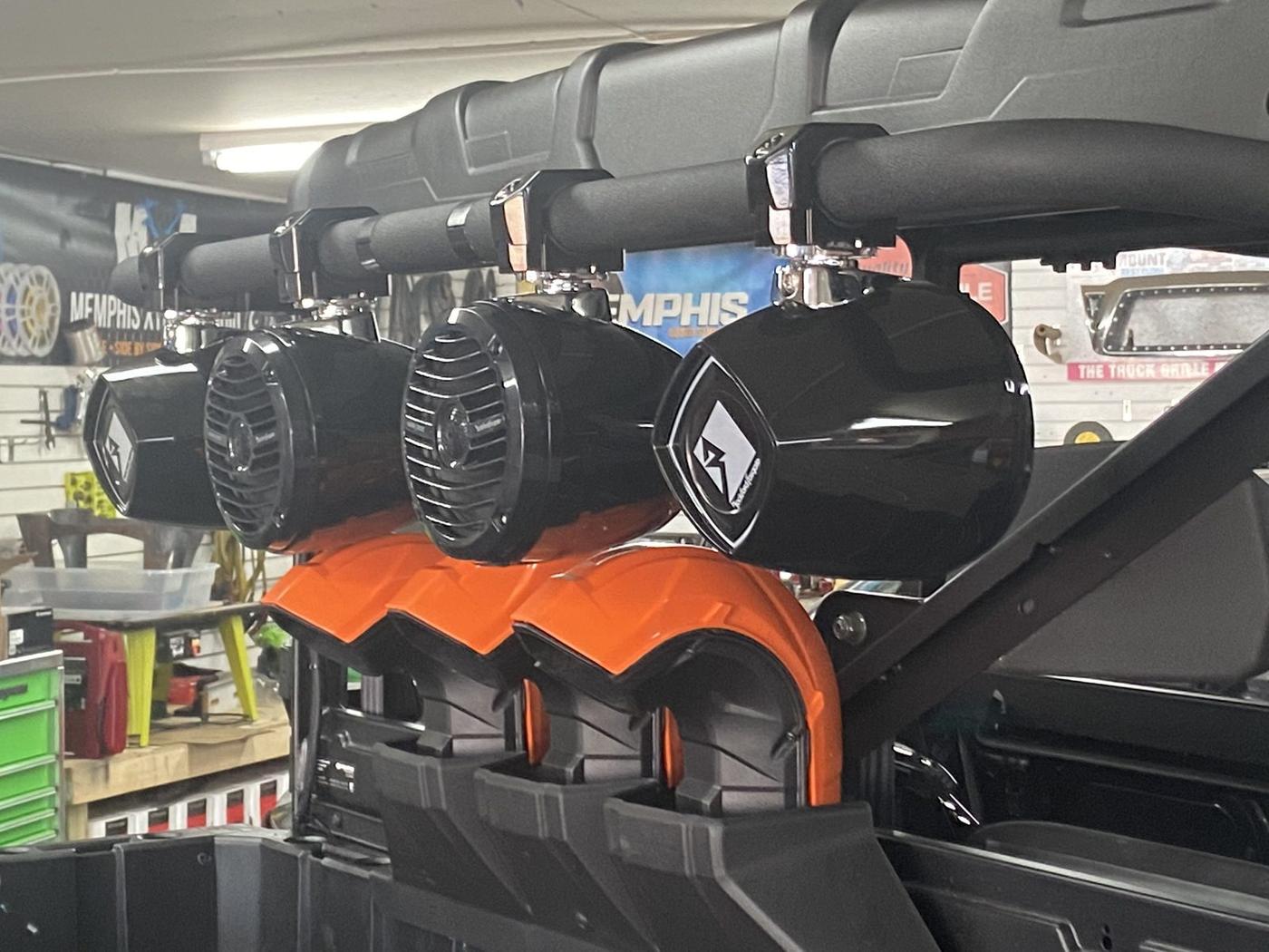 Speaker cans mounted on a UTV roll bar